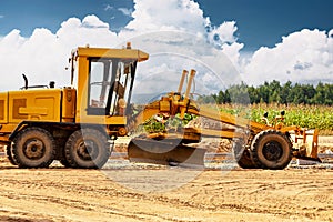 Road grader at the construction site. Powerful construction machine for ground leveling and excavation. Close-up. Professional