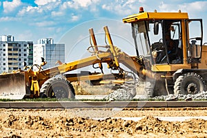 Road grader at the construction site. Powerful construction machine for ground leveling and excavation. Close-up. Professional