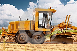 Road grader at the construction site. Powerful construction machine for ground leveling and excavation. Close-up. Professional