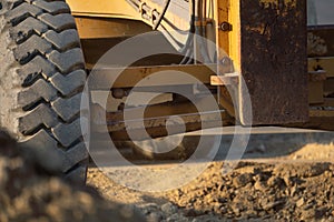 Road grader working at construction site for maintenance and construction of dirts and gravel road. Yellow motor grader. Heavy