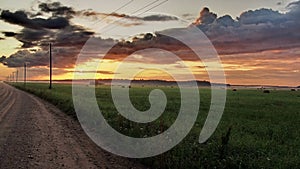 Road, green field and clouds at sunset