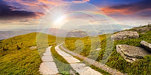 Road on a hillside near mountain peak at sunset