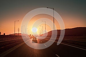 Road, infrastructure, transportation during sunset near a city, without smog, with amazing light and cars