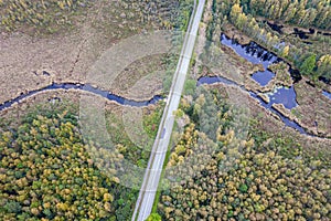 road intersecting blue river among autumn yellow forests, bogs