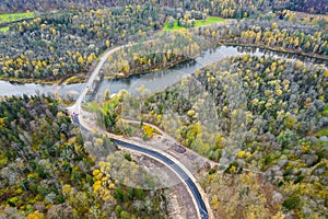 road intersecting blue river among autumn yellow green forests