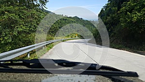 Road through jungle, view behind windshield of car