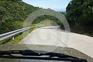 Road through jungle, view behind windshield of car