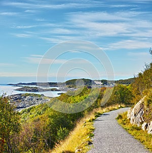 Road, landscape and sky with ocean in nature for travel, adventure and trees with mountain view in Norway. Path