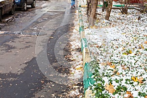 Road and lawn covered by the first snow in city