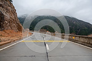 A road leading to the mountains. There is fog on the mountains