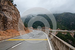 A road leading to the mountains. There is fog on the mountains