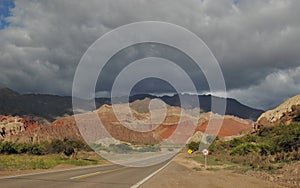 Road leading to vibrant colored rocks under a dramatic sky