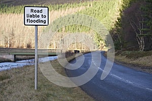 Road liable to flooding road safety sign by river in rural countryside