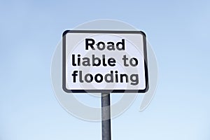 Road liable to flooding sign post against blue sky