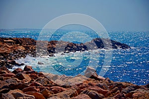 Road is made of stones, leading to the sea. Waves break on the rocks of a wild lonely beach. The Mediterranean Sea in Israel