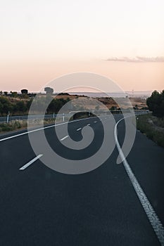 Road making a curve in a landscape of a sunset