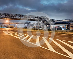 Road markings on bending road with oil refinery at night