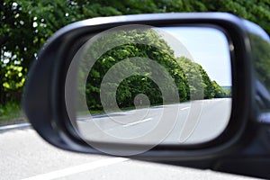The road with markings is reflected in the side view mirror