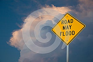 Road May Flood Sign Against A Blue Sky and Storm clouds.