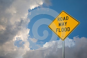 Road May Flood Sign Against A Blue Sky and Storm clouds.