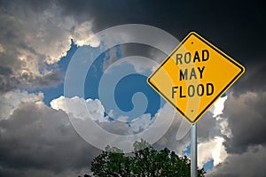 Road May Flood Sign Against Storm Clouds and A Tree.