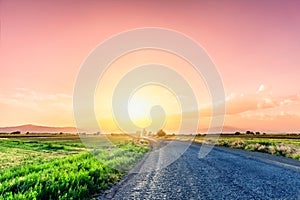 Road on meadow with beautiful sunset sky