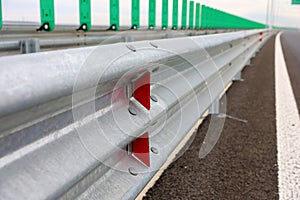 Road metal bump with red reflectors mounted on a new highway motorway after construction and repair in a cloudy day.