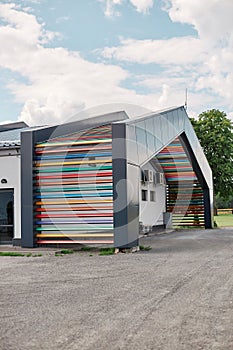 Road with modern building with beautiful creating wall with multicolored colorful wooden rails on facade