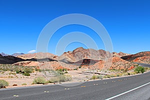 Road with a mountain backdrop under clear blue skies. Valley of Fire State Park, Nevada, USA
