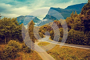 Road among mountains with dramatic stormy cloudy sky