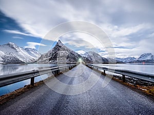 Road and mountains in the night, Lofoten islands, Norway. Asphalt and moonlight. Winter landscape with night sky. Long exposure sh