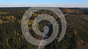 Road and moving cars between colorful autumn forest