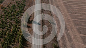 Road and moving cars between colorful autumn forest in Ural