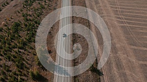 Road and moving cars between colorful autumn forest in Ural