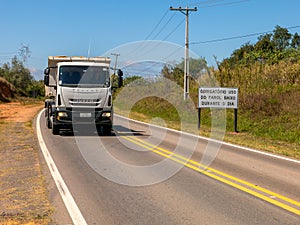 Road with a new traffic sign informing the new law that requires the use of headlights on even during the day on the roads with a