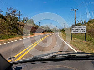 Road with a new traffic sign informing the new law that requires the use of headlights on even during the day on the roads seen fr