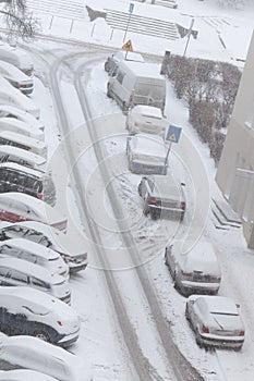 Road and parked cars covered in snow after blizzard