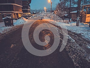 The road, partially cleared of snow. Traces of tires from the car in the snow. The beginning of winter in Bakuriani