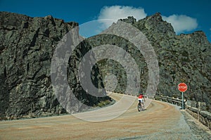 Road passing through rocky landscape with cyclist