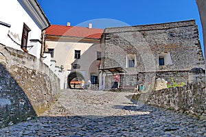 Road paved with gray cobblestone and tourists going far away