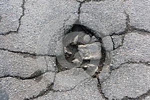 Road pit and cracks on the asphalt close-up macro. Background texture