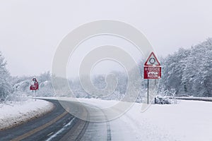 Road with Reduce speed now sign during snow fall