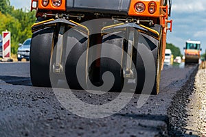 Road repair, compactor lays asphalt. Heavy special machines. Asphalt paver in operation. Side view. Closeup.