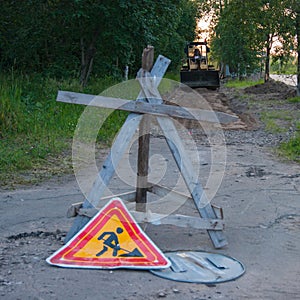 Road repair work - a yellow tractor stands on the sidewalk, which will repair. In the foreground is an anti-tank hedgehog and a