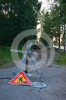 Road repair work - a yellow tractor stands on the sidewalk, which will repair. In the foreground is an anti-tank hedgehog and a