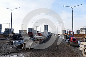 Road repair works at construction site. Construction road of city street  in a new residential quarter. Asphalt paver machine and