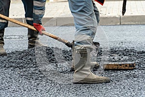 road repairs in the city. Filling holes and potholes on roads with fresh asphalt. Builders in boots and overalls with various