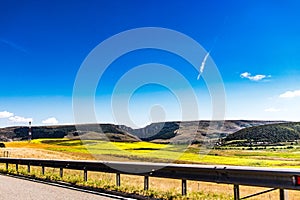 Road with road railing passing near sunflower field with a mountain scenery in the background