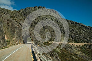 Road on rocky landscape passing through tunnel