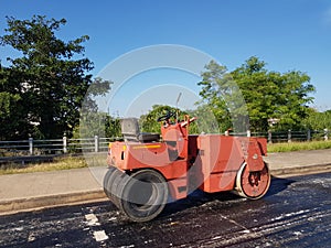 Road roller and asphalt compactor parked on the side of the road during lunch break